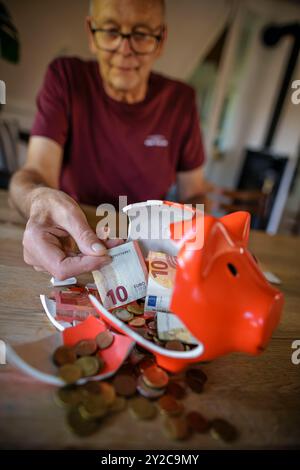 Berlin, Deutschland. 05th Sep, 2024. Photo symbolique sur le thème des finances dans la vieillesse - la pauvreté de la vieillesse. Un vieil homme est assis à la maison à la table devant une tirelire cassée et compte l'argent. Berlin, le 5 septembre 2024. Crédit : dpa/Alamy Live News Banque D'Images