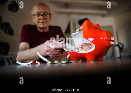 Berlin, Deutschland. 05th Sep, 2024. Photo symbolique sur le thème des finances dans la vieillesse - la pauvreté de la vieillesse. Un vieil homme est assis à la maison à la table devant une tirelire cassée et compte l'argent. Berlin, le 5 septembre 2024. Crédit : dpa/Alamy Live News Banque D'Images