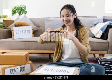 Jeune femme prenant des photos de boîtes de dons dans Living Room for Charity and Community support Banque D'Images