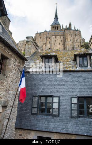 Perspective sur les bâtiments de l'abbaye du Mont Saint Michel en Normandie, France avec drapeau national Banque D'Images