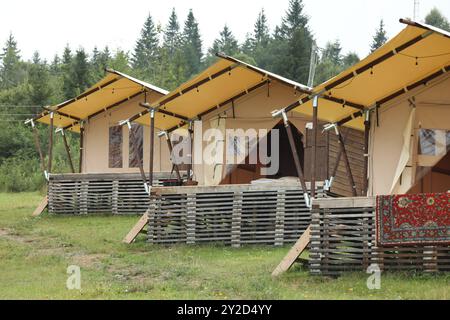 Nombreuses tentes et forêt verte dans les montagnes. Site de glamping Banque D'Images