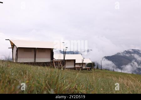 De nombreuses tentes et forêts couvertes de brouillard dans les montagnes. Site de glamping Banque D'Images