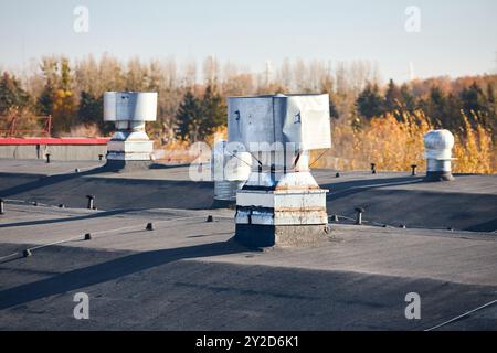 Système de ventilateur de ventilation d'évacuation de toit d'air de grand bâtiment commercial industriel. Cheminées à capuche conduits et conduits en rangée sur le toit, foyer sélectif Banque D'Images