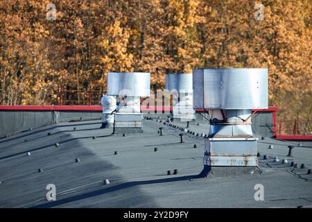 Système de ventilateur de ventilation d'évacuation de toit d'air de grand bâtiment commercial industriel. Cheminées à capuche conduits et conduits en rangée sur le toit, foyer sélectif Banque D'Images