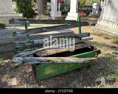 Vieux banc brisé en ruine dans le cimetière public Banque D'Images