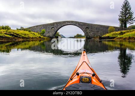 Kayak de mer dans le Clachan Sound approchant du 'pont sur l'Atlantique' sur la côte ouest de l'Écosse Banque D'Images