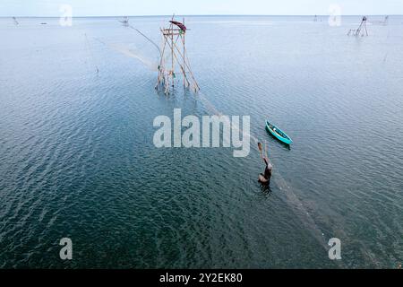 Vue aérienne d'un pêcheur fixant un filet de pêche et vue d'une tour de pêche en bois avec sur la côte de la mer au nord de Makassar à Sulawesi, Indonésie Banque D'Images