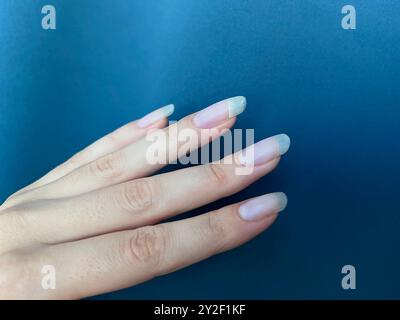 Clou cassé. Les ongles longs naturels féminins se rapprochent. Manucure avec ongle fissuré. Banque D'Images