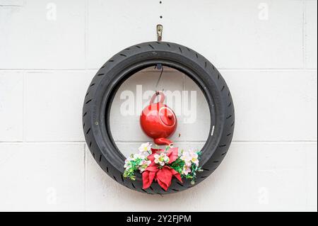 Plantes artificielles exposées dans de vieux pneus sur un mur de jardin Banque D'Images