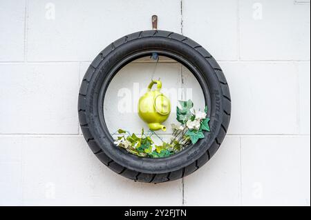 Plantes artificielles exposées dans de vieux pneus sur un mur de jardin Banque D'Images