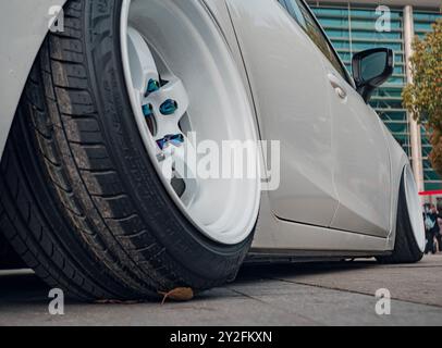 Suzhou, Chine - 30 mars 2019 : gros plan d'une roue de voiture personnalisée lors d'un salon automobile, avec le côté de la voiture et le bâtiment en arrière-plan. Banque D'Images