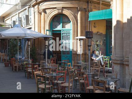 Nicosie, Chypre - 03 décembre 2015 : Café en plein air à Nicosie avec un serveur préparant des tables et un client se relaxant Banque D'Images