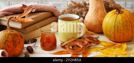 Belle composition d'automne avec une tasse de thé, des livres, de la confiture savoureuse et des craquelins sur une table blanche Banque D'Images