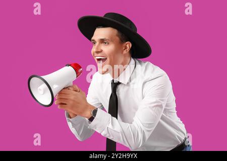 Jeune homme criant dans mégaphone sur fond violet Banque D'Images