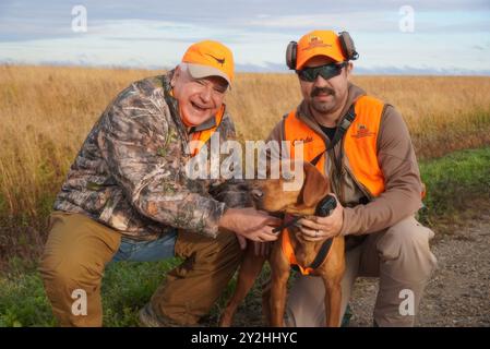 Owatonna (États-Unis d'Amérique). 14 octobre 2023. Le gouverneur du Minnesota Tim Walz, d-MN, à gauche, pose avec un chien de chasse et un compagnon de chasse lors de l'ouverture de la saison de chasse des faisans, le 14 octobre 2023 à Owatonna, Minnesota. Crédit : MNGOV/Minnesota Governors Office/Alamy Live News Banque D'Images