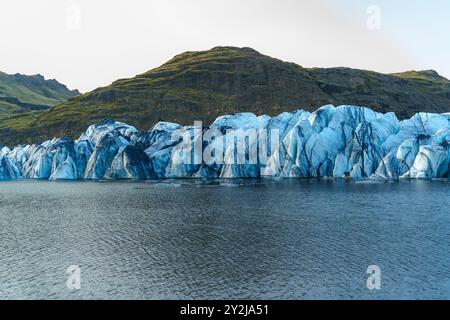 Le glacier de Sólheimajökull s'étend des montagnes jusqu'à un lac serein, mettant en valeur le magnifique paysage glacé de l'Islande Banque D'Images