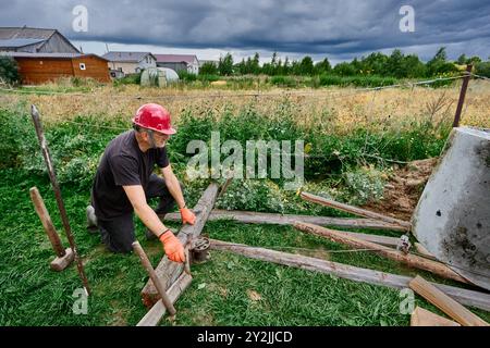 Lors de l'installation d'anneaux en béton dans une nouvelle fosse septique, le travailleur utilise un système de rouleaux et un treuil. Banque D'Images