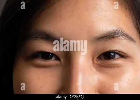 Au bureau, gros plan du visage de la femme asiatique, montrant l'expression, avec arrière-plan flou Banque D'Images