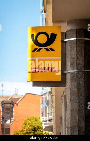 Coblence, Allemagne - 7 septembre 2024 : un panneau jaune vif affichant le logo DHL est monté sur un bâtiment. Le ciel bleu clair fournit un BA joyeux Banque D'Images