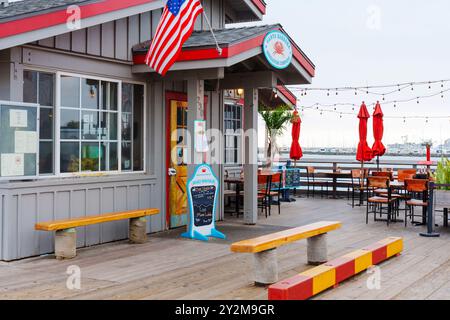 Santa Barbara, Californie - 20 avril 2024 : salle à manger extérieure avec parasols rouges et tables en bois dans un restaurant côtier à Santa Barbara, parfait Banque D'Images