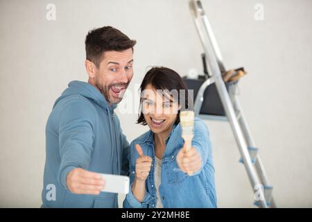 couple à la maison peinture murs prenant selfie avec smartphone Banque D'Images