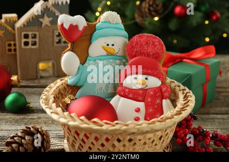 Délicieux biscuits en forme de bonhommes de neige et décor de Noël sur une table en bois, gros plan Banque D'Images