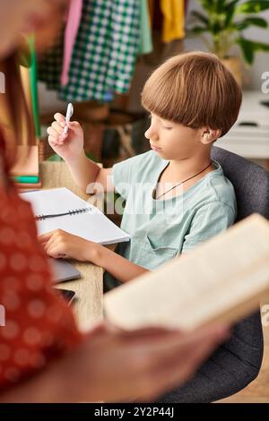 Une mère s'entretient avec son fils malentendant pendant qu'il se concentre sur ses études. Banque D'Images