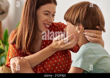 Une mère aimante s'engage avec son fils malentendant, favorisant la connexion et la joie. Banque D'Images