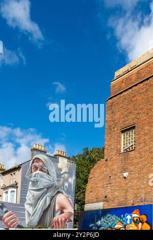 Figurine murale masquée à capuche lors de l'événement artistique graffiti Southend City Jam à Southend on Sea, Essex, Royaume-Uni. Propriété de fin. Vieux cinéma partiellement démoli Banque D'Images