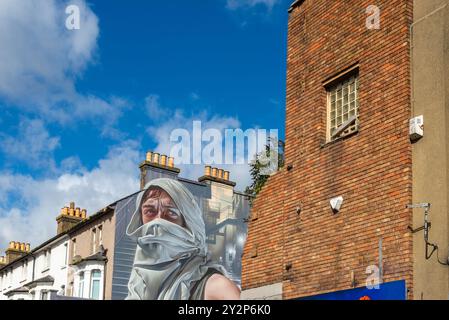 Figurine murale masquée à capuche lors de l'événement artistique graffiti Southend City Jam à Southend on Sea, Essex, Royaume-Uni. Propriété de fin. Vieux cinéma partiellement démoli Banque D'Images