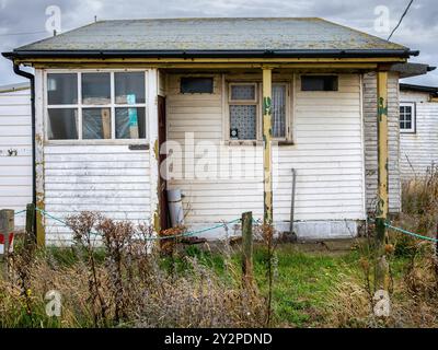 Une maison solennelle en bois se dresse sur le front de mer de Dungeness, à l'ombre d'un ciel nuageux Banque D'Images