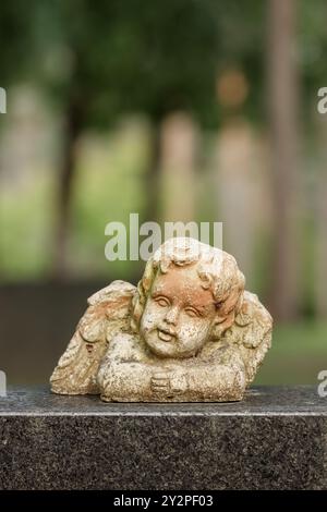 Vieil ornement ange usé sur la pierre tombale. Les anges sont des décorations populaires dans les cimetières. L'image comporte un espace vide pour le texte. Un jour d'automne nuageux. Banque D'Images