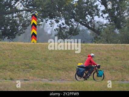 Reitwein, Allemagne. 11 septembre 2024. Un cycliste roule sous la pluie sur la piste cyclable Oder-Neisse dans l'Oderbruch à l'est du Brandebourg. Le temps d'automne continue à Berlin et Brandebourg. Des orages locaux sont attendus - et les températures chutent, selon le Service météorologique allemand (DWD). Crédit : Patrick Pleul/dpa/Alamy Live News Banque D'Images