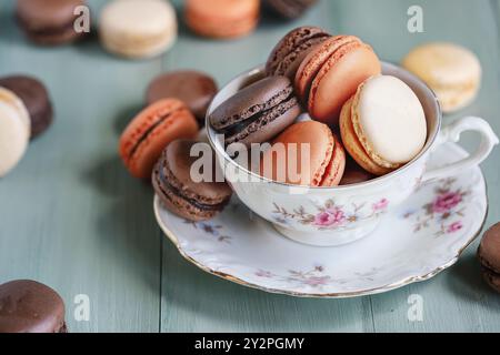 Tasse de thé ancienne remplie d'une variété de chocolat français frais et de macarons à l'orange. Mise au point sélective avec avant-plan et arrière-plan flous. Banque D'Images