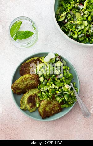 Crêpes aux courgettes et au brocoli servies avec une salade mixte de concombres, jeunes pois et radis. Ce plat végétarien sain est à la fois délicieux et nu Banque D'Images