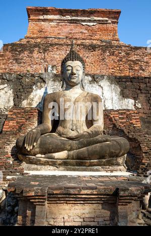 Sculpture d'un Bouddha assis sur les ruines antiques du temple bouddhiste Wat Mahathat. Parc historique de Sukhothai, Thaïlande Banque D'Images