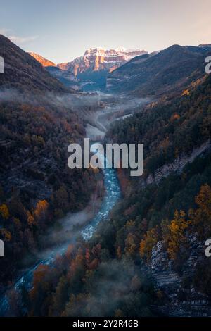 Une vue aérienne enchanteresse capture la vallée d'Ordesa baignée dans les teintes de l'automne avec la rivière Ara serpentant à travers les majestueuses montagnes de l'Aragon Banque D'Images