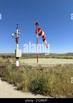 Une vue détaillée d'une zone d'atterrissage d'urgence d'hélicoptère dans un cadre rural, avec une chaussette à vent rouge et blanche proéminente et diverses conditions météorologiques dedans Banque D'Images