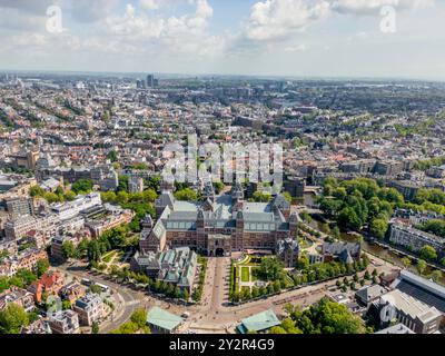 Vue d'en haut, cette image capture une vue aérienne vibrante d'une ville animée disséquée par des voies navigables sereines et mettant en valeur un maste architectural historique Banque D'Images