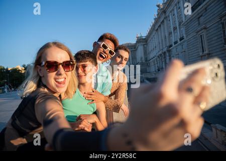 Un groupe d'amis LGBTQIA+ capturent un joyeux moment selfie par une journée ensoleillée dans la ville, près du Street art inspiré de la nature à . Banque D'Images