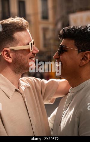 Une scène chaleureuse et affectueuse d’un couple gay multiethnique partageant un moment joyeux par une journée ensoleillée. Les deux hommes sont souriants, habillés de façon décontractée, et semblent des Dee Banque D'Images