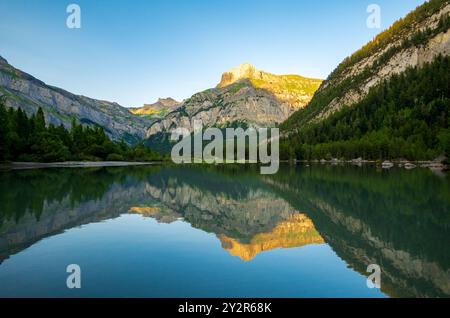 Une scène sereine capturant les eaux tranquilles du lac Derborance reflétant les Alpes suisses environnantes soulignées par le lever du soleil doré Banque D'Images