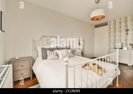 Cette chambre confortable et élégante dispose d''un lit double classique et d''un lit bébé blanc, décorée dans des tons doux et neutres et d''un mobilier élégant. Banque D'Images