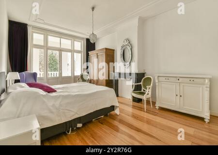 Cette chambre bien éclairée présente un décor classique avec de hauts plafonds, du parquet et un mobilier de style vintage. Banque D'Images