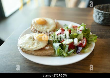 Deux toasts avec oeuf poché et salade avec épinards, tomates cerises et mozzarella, ingrédients sur la table du petit déjeuner, plat végétarien appétissant, blanc Banque D'Images