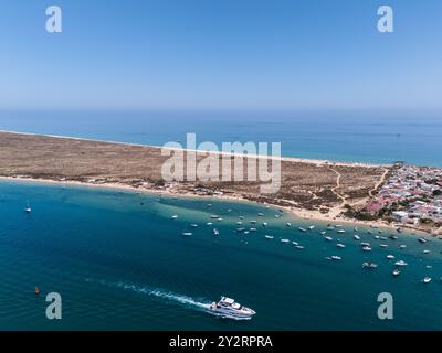 Vue aérienne d'une ville côtière avec des bateaux ancrés dans les eaux bleues et une plage de sable sous un ciel clair. Banque D'Images