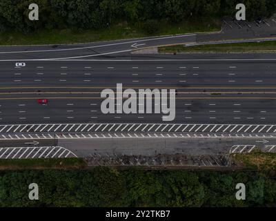 Une vue aérienne d'une large parkway avec deux voitures sur la route, passant à travers des bois denses par un matin nuageux Banque D'Images