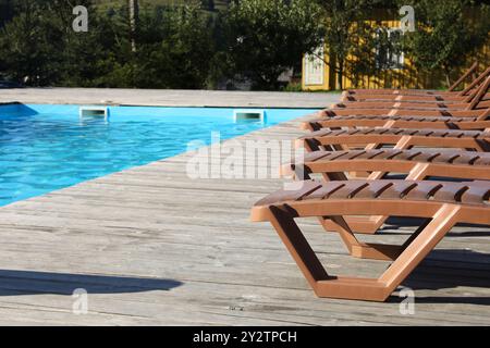 Chaises longues vides sur la terrasse en bois près de la piscine extérieure Banque D'Images