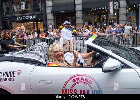 Une scène vibrante d'un défilé de fierté mettant en vedette Miss Major, grand maréchal, brandissant depuis une voiture décapotable avec une foule enthousiaste en arrière-plan. Banque D'Images