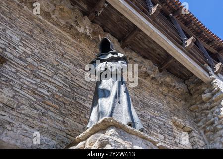 Tallinn, Estonie - 8 mai 2024 : une statue solitaire d'un moine sans visage surplombe le paysage urbain historique de Tallinn. Les mains du moine sont serrées dans la prière Banque D'Images